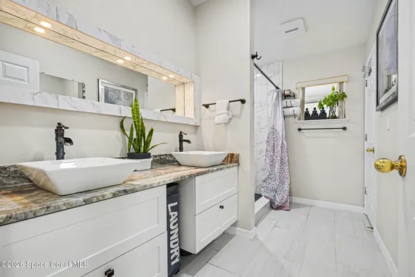 a bathroom with a granite countertop sink a mirror and shower
