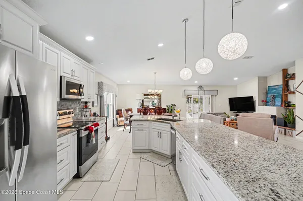 a large kitchen with stainless steel appliances granite countertop a sink dishwasher a refrigerator and a fireplace with wooden floor