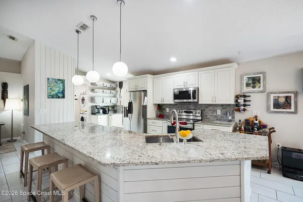 a kitchen with stainless steel appliances granite countertop a sink counter space and a living room view