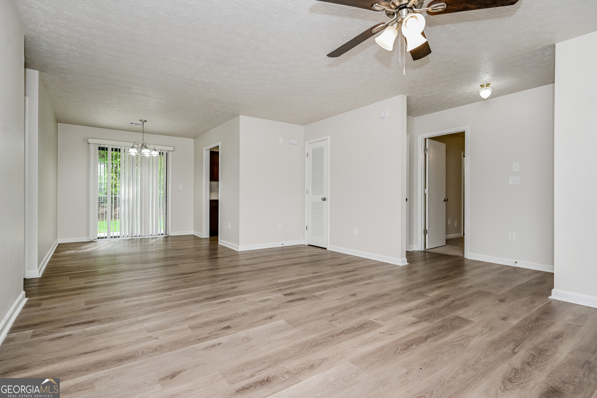 2140 Teri Lane Southeast Conyers, GA 30013 - Photo 3 of 16 an empty room with wooden floor chandelier fan and windows
