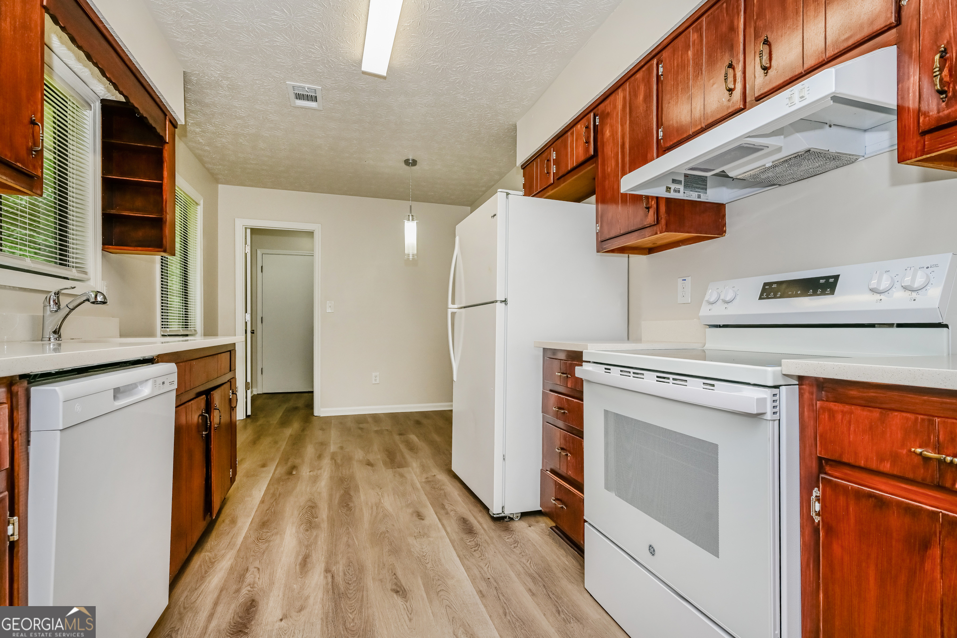 2140 Teri Lane Southeast Conyers, GA 30013 - Photo 5 of 16 a kitchen with stainless steel appliances granite countertop a refrigerator a stove and a sink with wooden floor