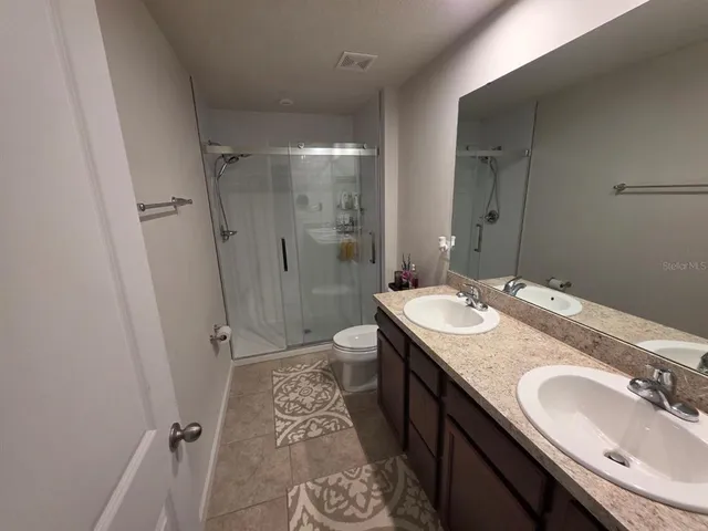 a bathroom with a granite countertop sink a mirror and a shower