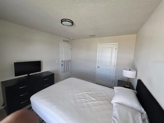 a bedroom with a bed and a flat tv screen on dresser