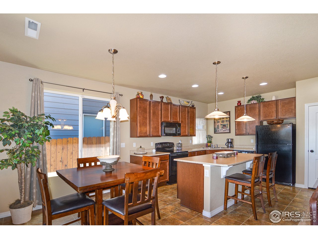 2045 Reed Grass Way Colorado Springs, CO 80915 - Photo 13 of 33 a kitchen with stainless steel appliances kitchen island granite countertop a table chairs and a refrigerator