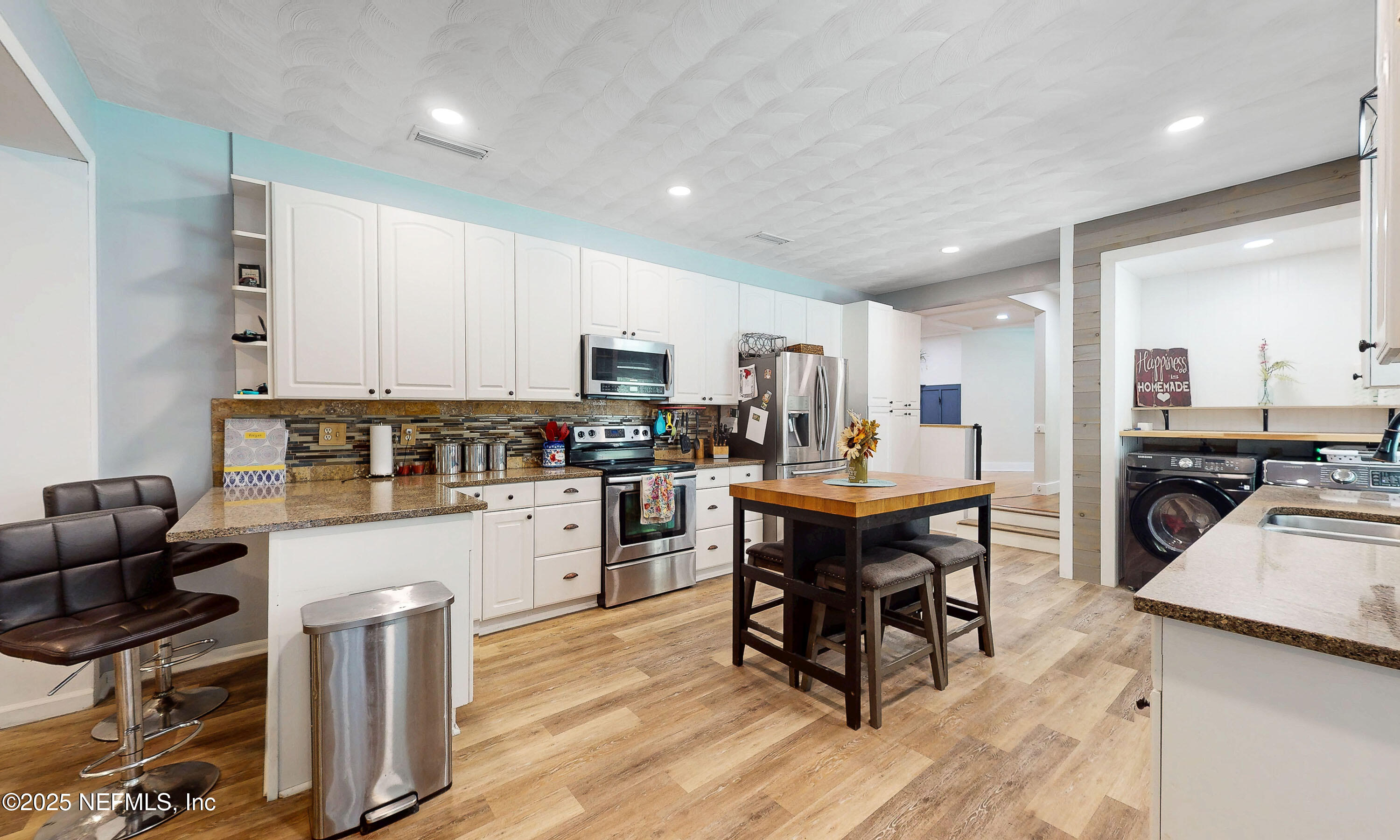 90 Forest Street Keystone Heights, FL 32656 - Photo 11 of 42 a kitchen with stainless steel appliances kitchen island granite countertop a refrigerator a stove a sink a dining table and chairs with wooden floor