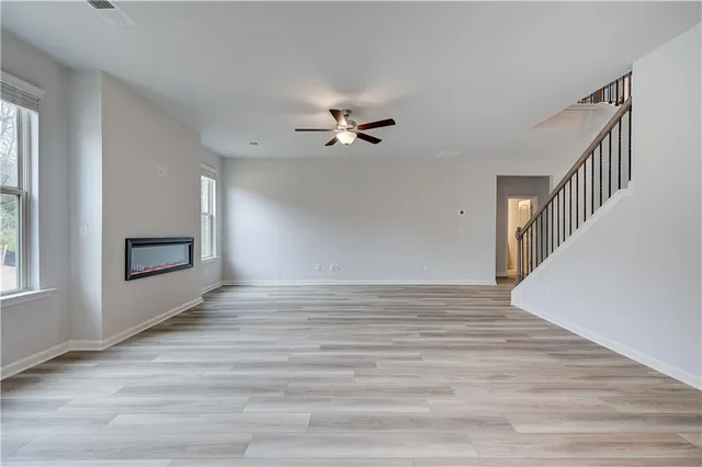 a view of an empty room with chandelier fan and wooden floor