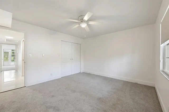 an empty room with a ceiling fan and window