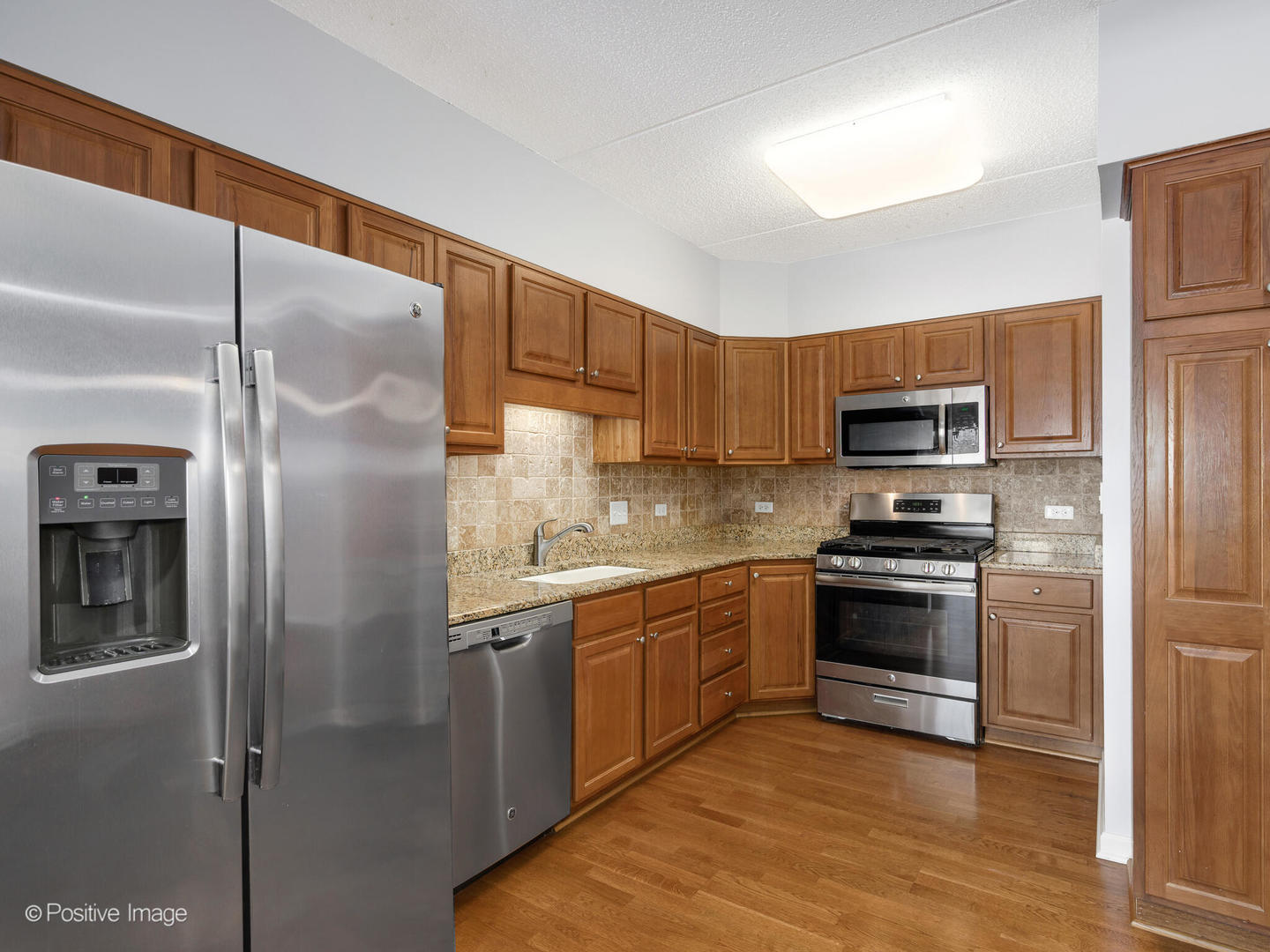 601 West Rand Road, Unit 307 Arlington Heights, IL 60004 - Photo 6 of 22 a kitchen with stainless steel appliances granite countertop a refrigerator a stove and a sink with wooden floor