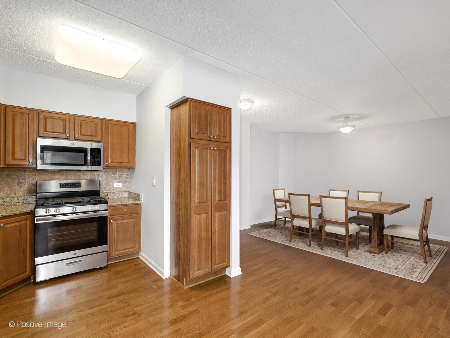 601 West Rand Road, Unit 307 Arlington Heights, IL 60004 - Photo 8 of 22 a kitchen with stainless steel appliances wooden floor and chairs