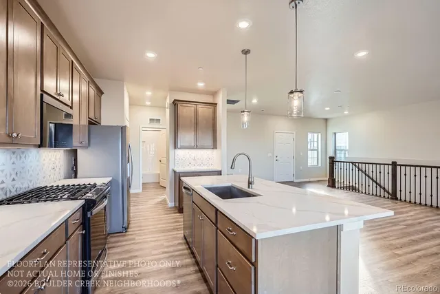 a kitchen with stainless steel appliances granite countertop a sink a stove and a wooden floors