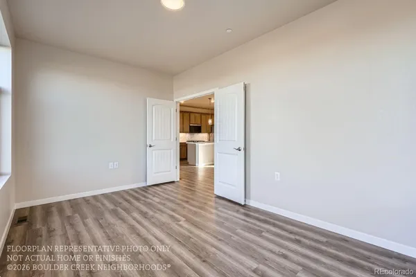 a view of a room with wooden floor and a kitchen