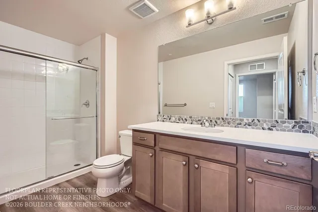 a spacious bathroom with a granite countertop sink toilet mirror and a shower