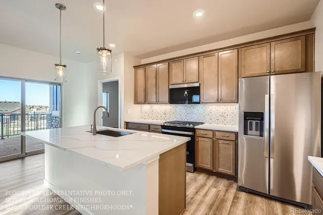 a kitchen with stainless steel appliances granite countertop a sink a stove a refrigerator a center island with wooden floor and cabinets