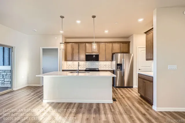 a view of kitchen with stainless steel appliances granite countertop a refrigerator a sink dishwasher a stove and a dining table with wooden floor