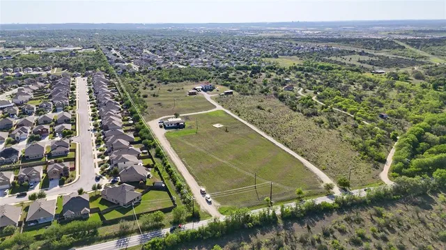 an aerial view of residential houses with outdoor space and trees