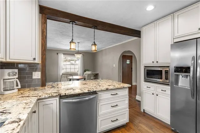 a kitchen with granite countertop a sink stainless steel appliances and white cabinets