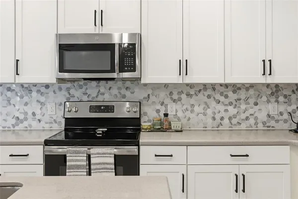 a kitchen with stainless steel appliances white cabinets and a stove a oven with white countertops