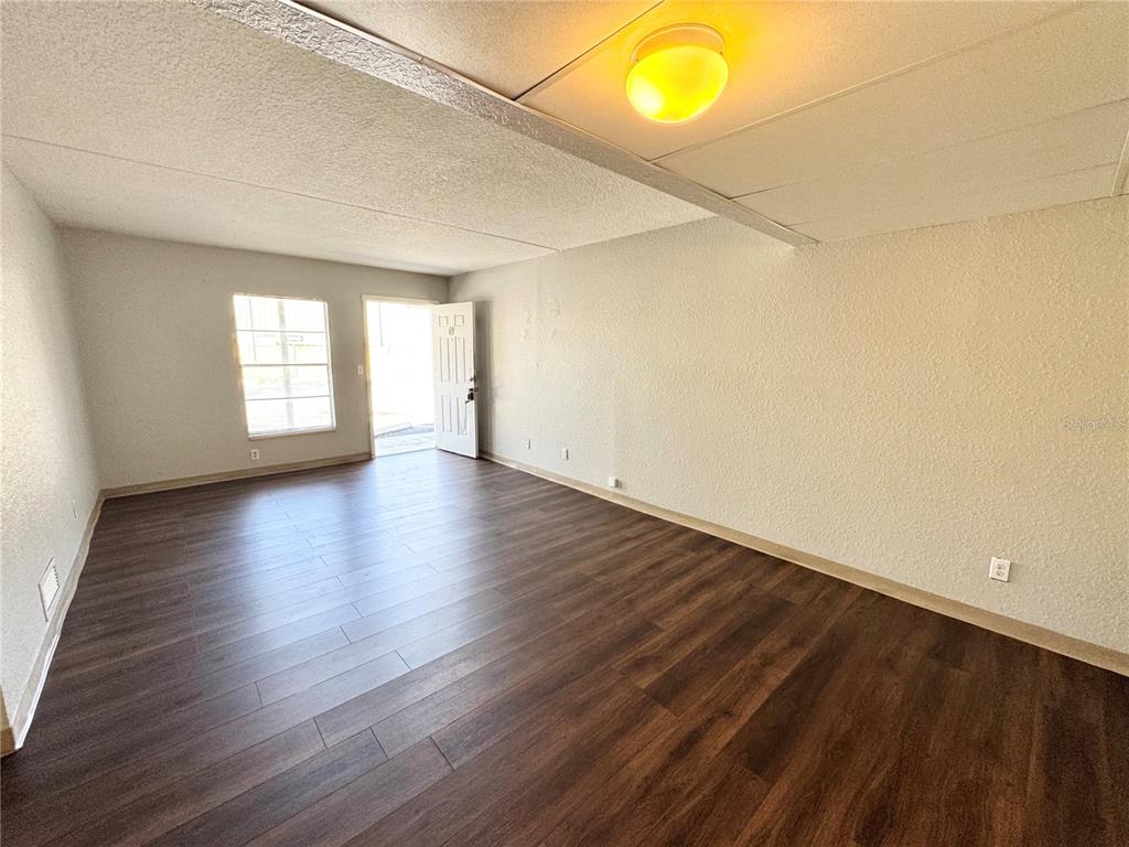 1229 Kennedy Road, Unit 69 Daytona Beach, FL 32117 - Photo 5 of 16 an empty room with wooden floor and windows