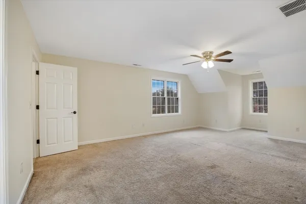 a view of an empty room with chandelier fan