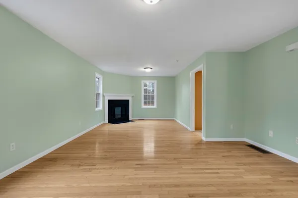 a view of empty room with wooden floor and fireplace