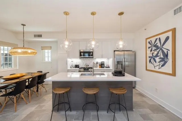 a kitchen with stainless steel appliances kitchen island a table and chairs in it