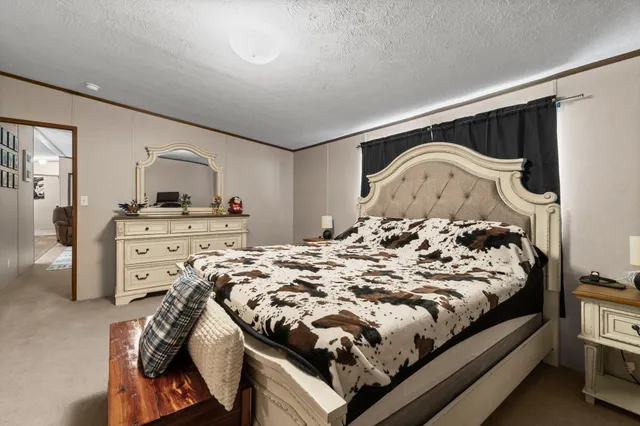 a bed sitting in a bedroom next to a window and dresser