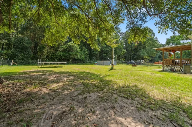 a view of a swimming pool with lawn chairs and large trees