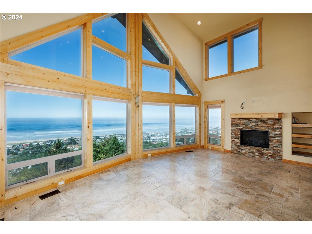 367 South Longview Loop Rockaway Beach, OR 97136 - Photo 13 of 43 a view of an empty room with a fireplace and a floor to ceiling window