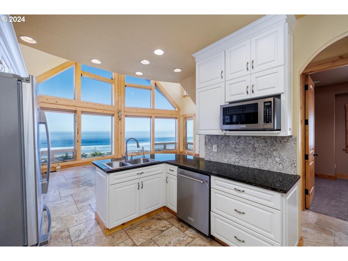 367 South Longview Loop Rockaway Beach, OR 97136 - Photo 27 of 43 a kitchen with stainless steel appliances kitchen island granite countertop a sink and cabinets