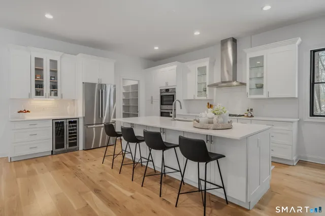a kitchen with stainless steel appliances kitchen island granite countertop a kitchen island hardwood floor and a sink