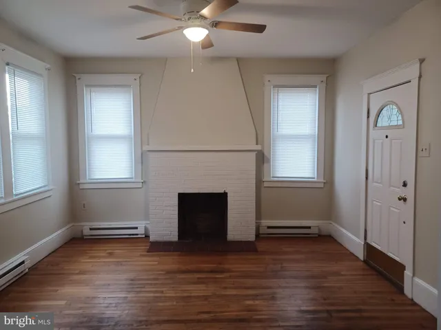 an empty room with wooden floor a ceiling fan and windows