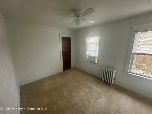an empty room with windows and ceiling fan