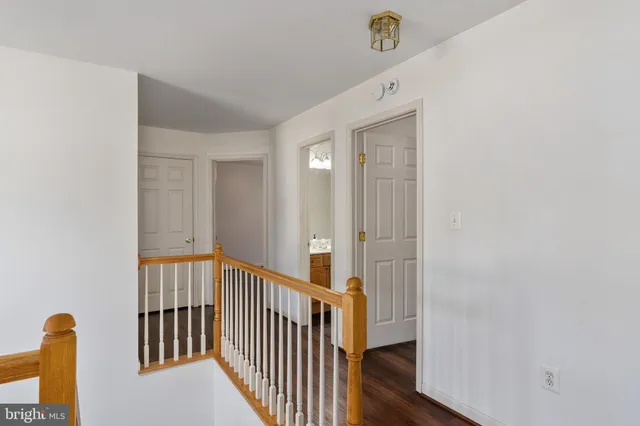 a view of a hallway to a room with wooden floor and windows