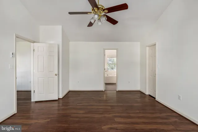 an empty room with wooden floor ceiling fan and window