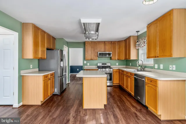 a kitchen with stainless steel appliances a refrigerator a stove top oven a sink dishwasher and wooden cabinets