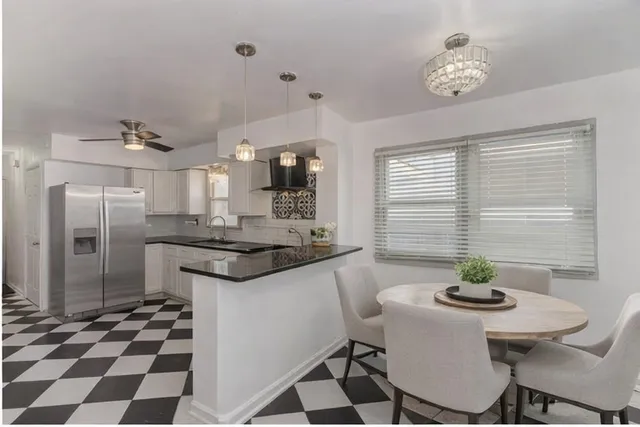 a kitchen with stainless steel appliances granite countertop a sink a stove a refrigerator a dining table and chairs