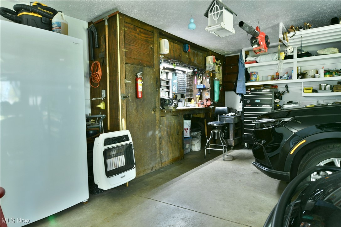 379 Housel Craft Road Bristolville, OH 44402 - Photo 44 of 50 Garage featuring heating unit, a workshop area, and freestanding refrigerator