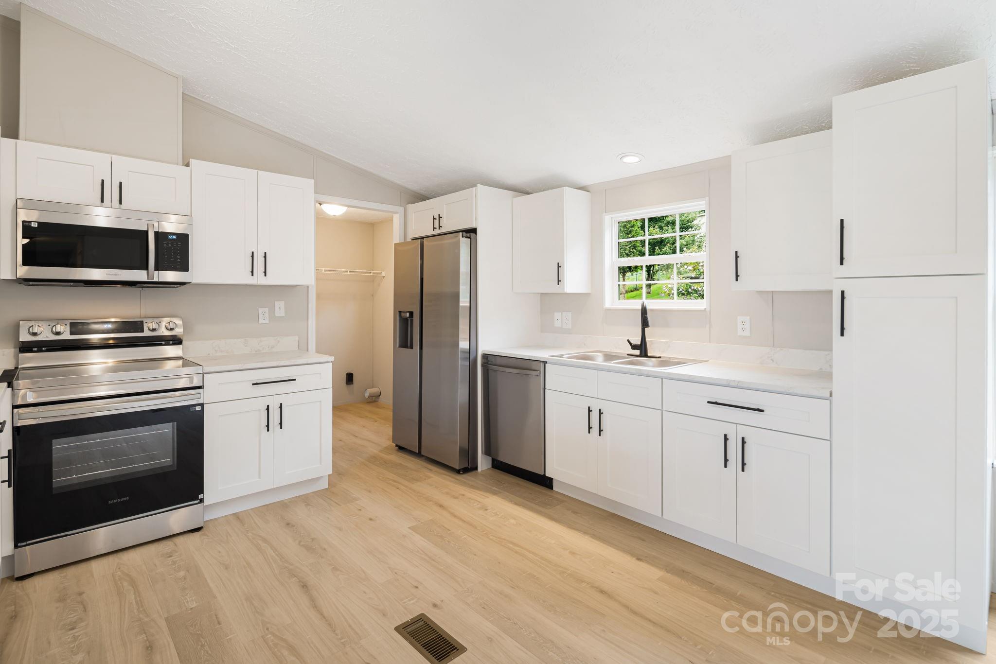 21 Toms Road Candler, NC 28715 - Photo 11 of 29 a kitchen with white cabinets white stainless steel appliances and sink
