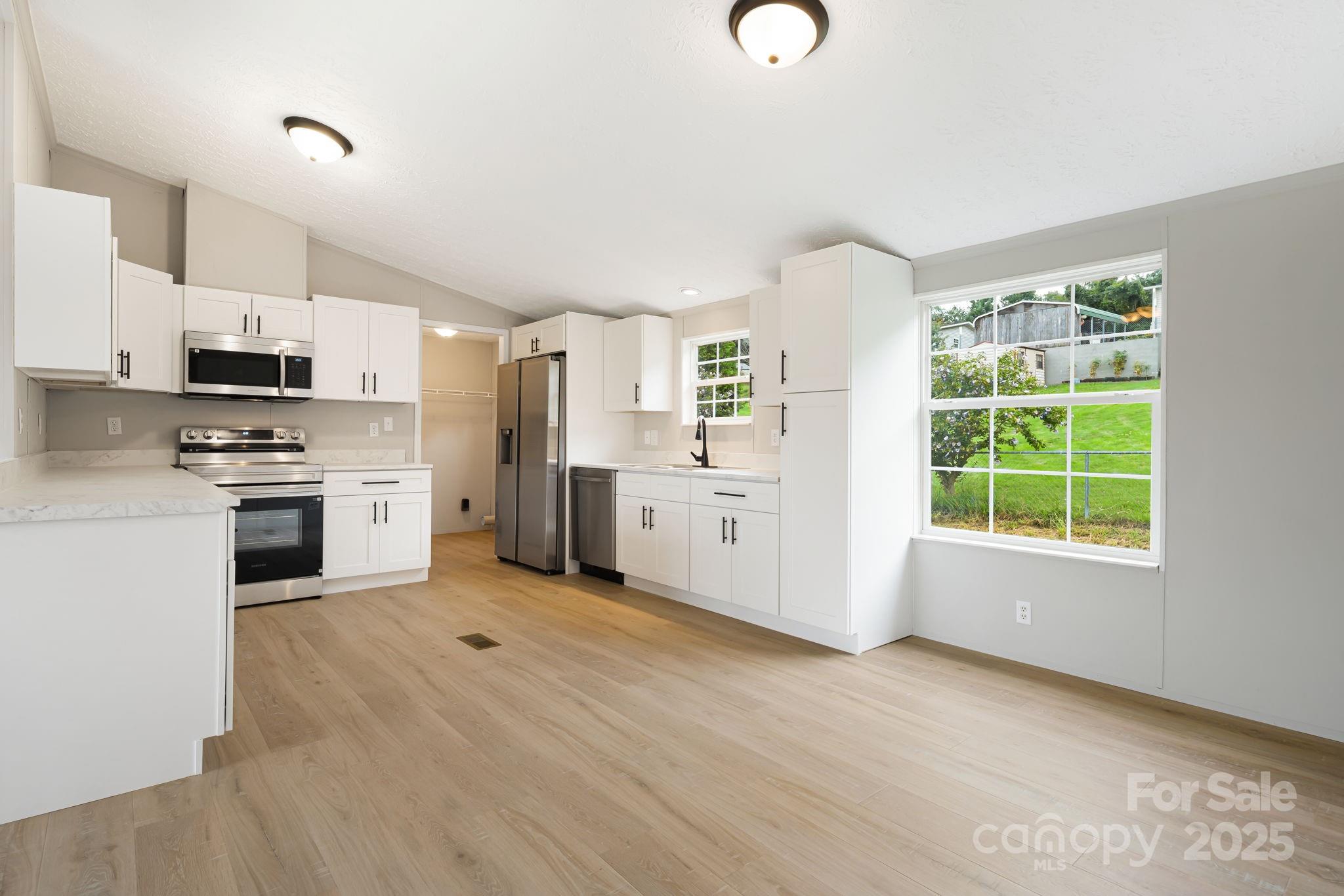 21 Toms Road Candler, NC 28715 - Photo 8 of 29 a kitchen with stainless steel appliances a stove top oven a sink a window and a refrigerator