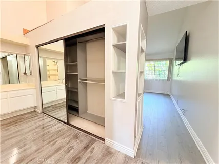 a view of a hallway with wooden floor and a bathroom