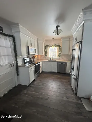 a kitchen with stainless steel appliances a refrigerator a sink dishwasher a stove top oven a refrigerator and cabinets