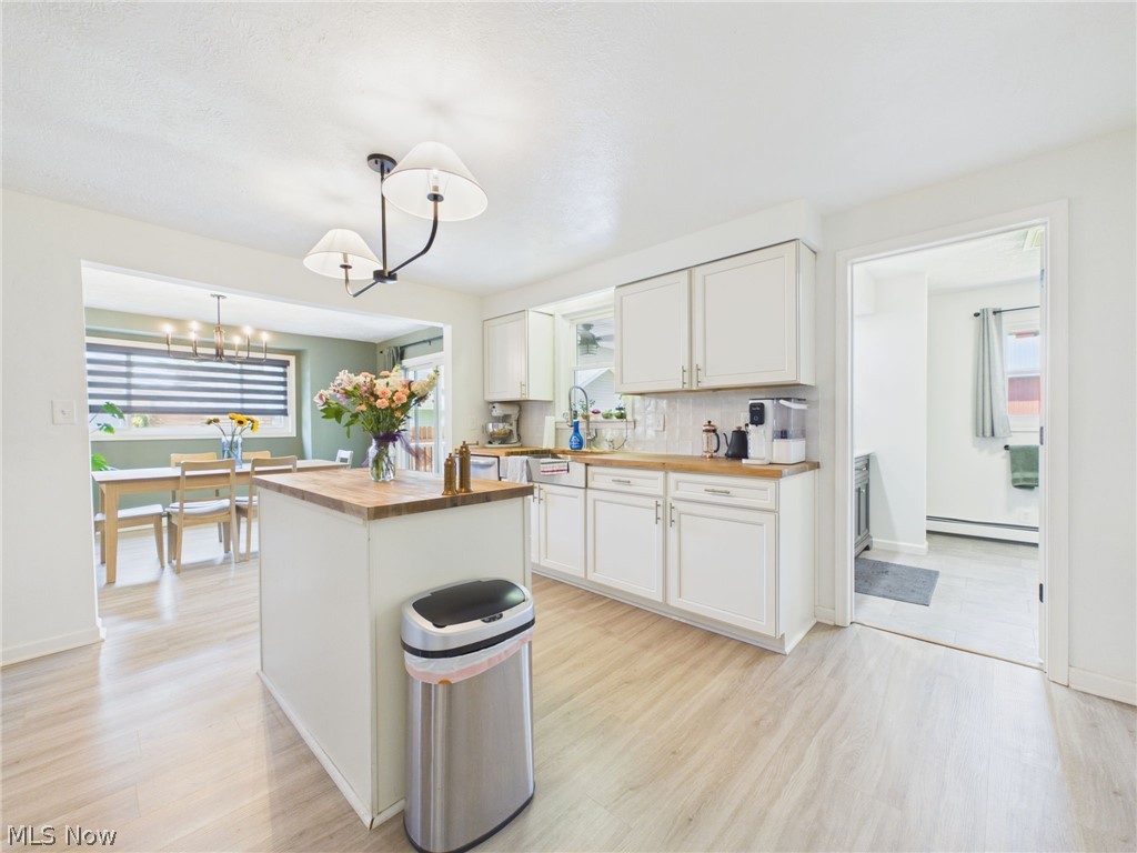3490 County Line Road Madison, OH 44057 - Photo 4 of 42 Bright kitchen featuring a central island with a wood-finish countertop, white cabinetry with gold-tone hardware, and wood-finish flooring