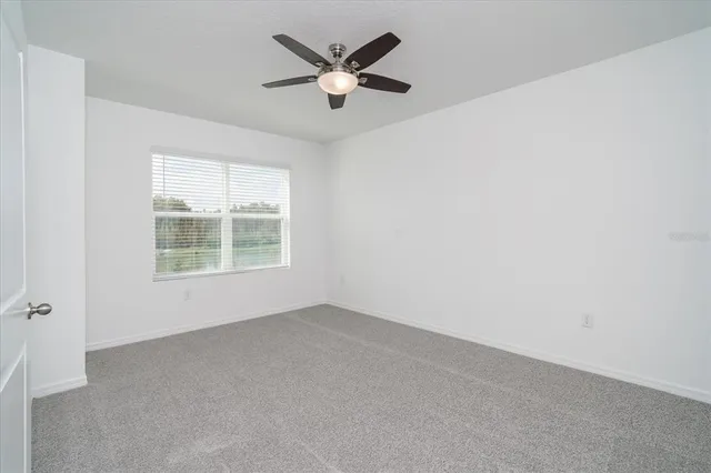 an empty room with a window and a ceiling fan