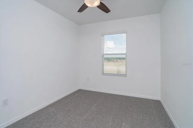 an empty room with a window and a ceiling fan