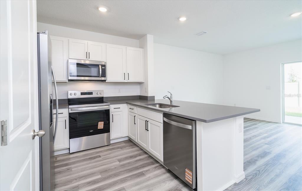 2466 Riversong Ldg Lane Wesley Chapel, FL 33543 - Photo 5 of 33 a kitchen with stainless steel appliances a stove microwave and sink