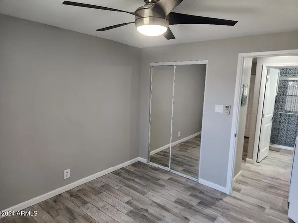 an empty room with wooden floor cabinet and windows