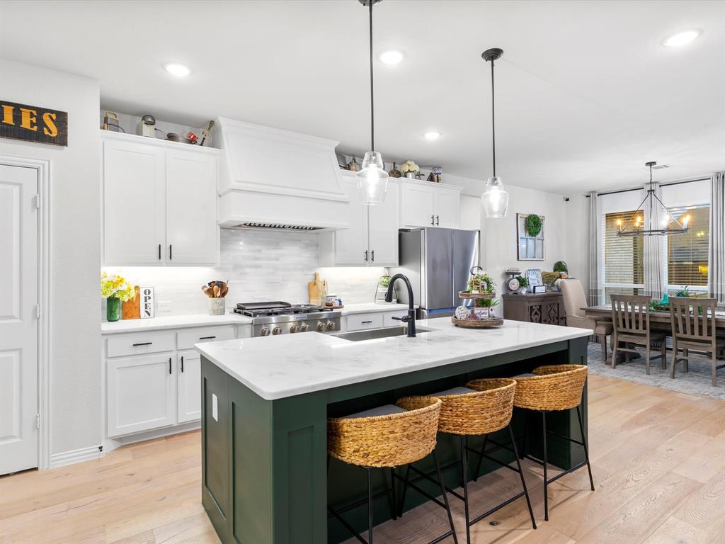 a kitchen with stainless steel appliances granite countertop a sink a stove and a wooden floors