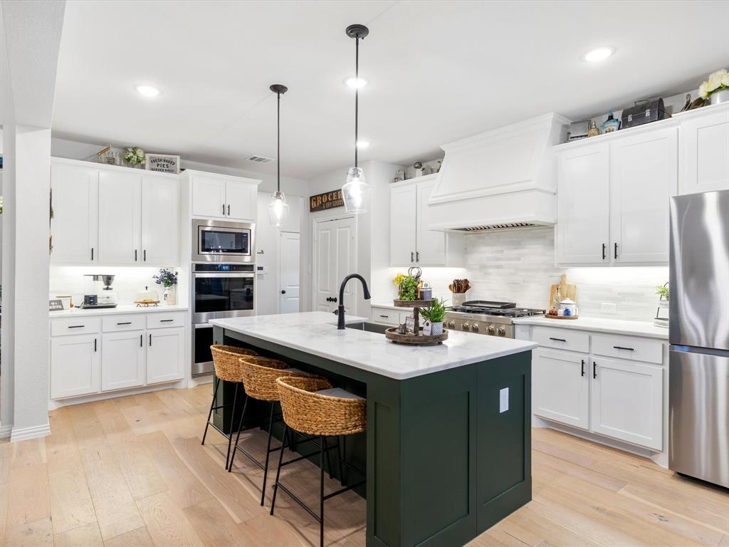 2156 Cloverfern Way Haslet, TX 76052 - Photo 9 of 40 a kitchen with stainless steel appliances kitchen island granite countertop a sink a stove a refrigerator and white cabinets with wooden floor