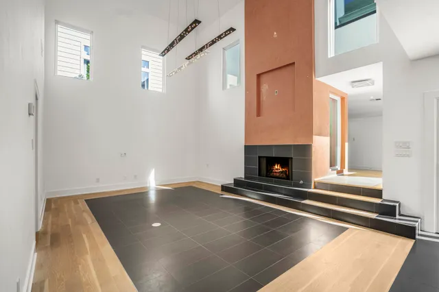 a view of an empty room with wooden floor and a fireplace