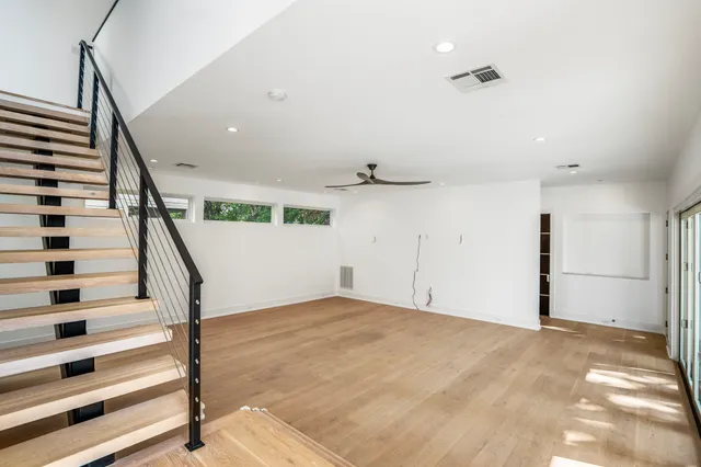 a view of an empty room with stairs and wooden floor